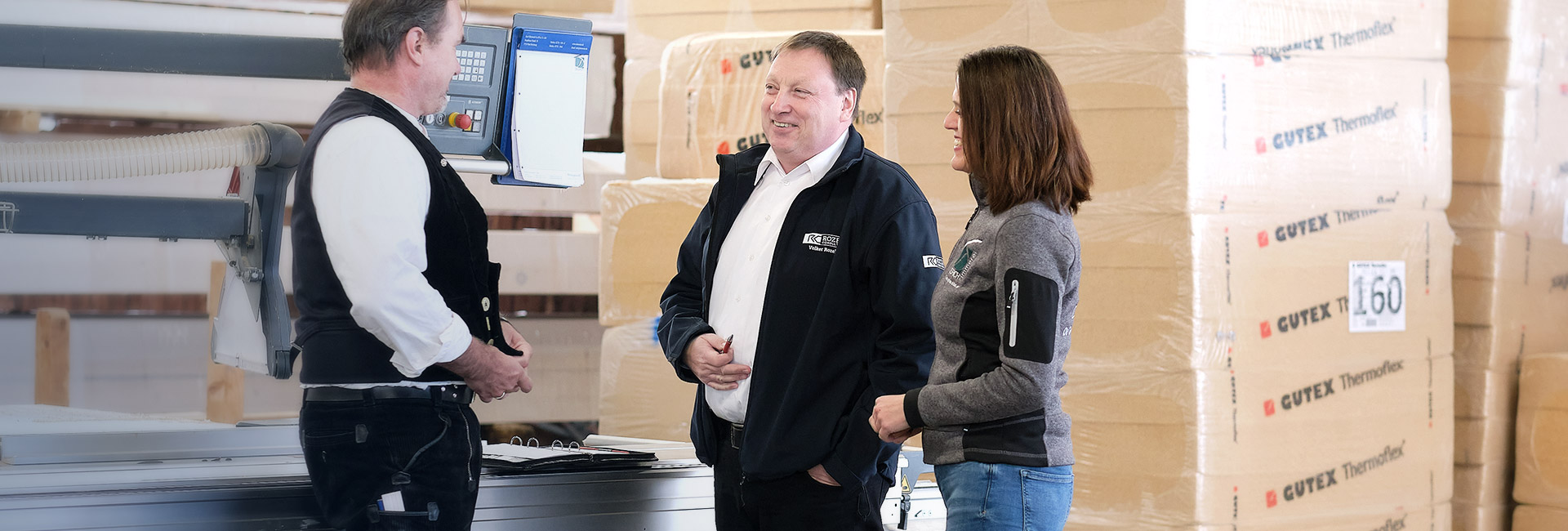 Volker Rozek stimmt in der Werkshalle mit dem Geschäftsführer und der Geschäftsführerin konkrete Maßnahmen zur Verbesserung der Produktionsabläufe ab.